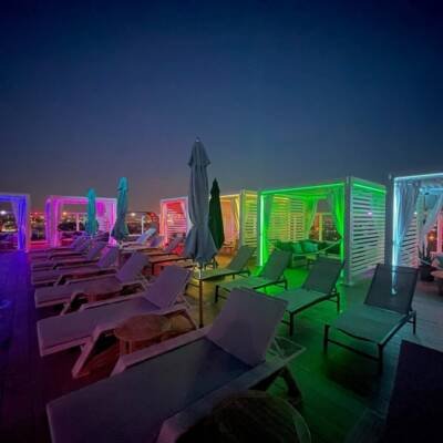 Cabana X cabanas lit in color beside a pool at night