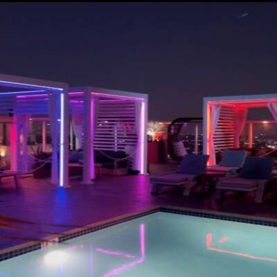 Rooftop Cabana X cabanas glowing in color around a pool