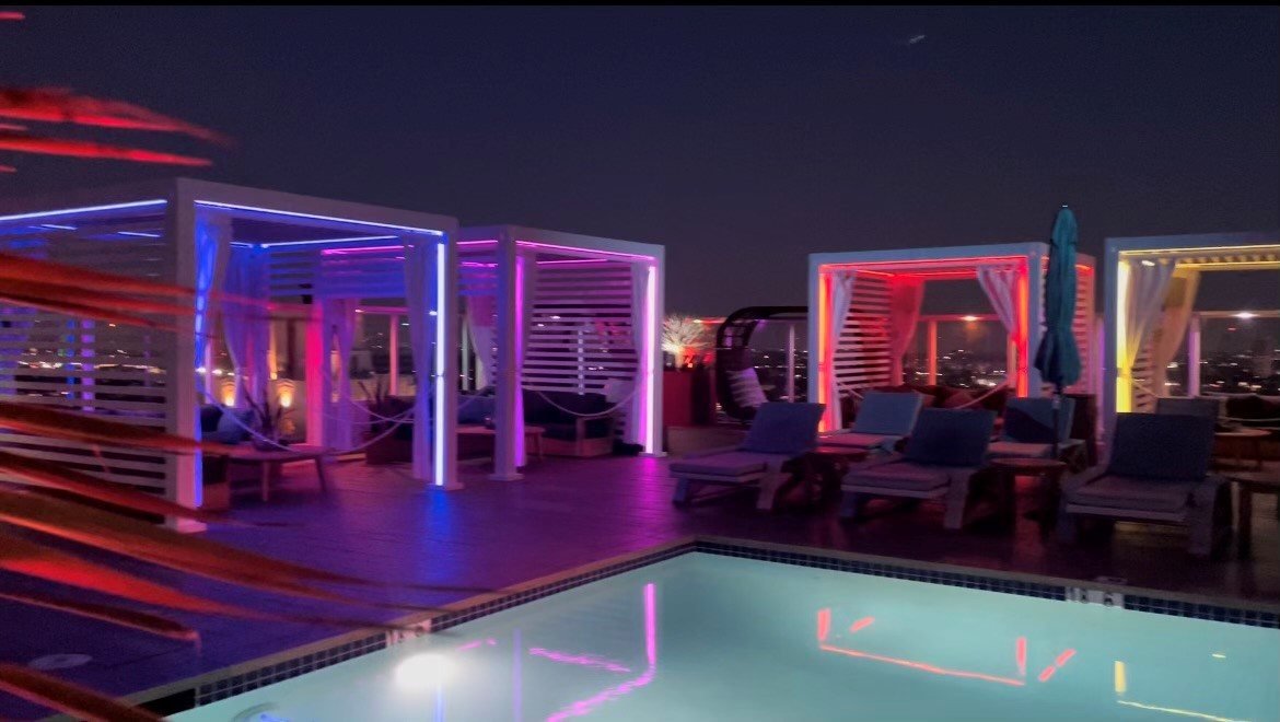 Rooftop Cabana X cabanas glowing in color around a pool