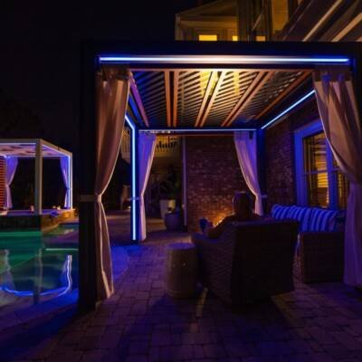 Cabanas lit with blue LED lighting beside a pool at night