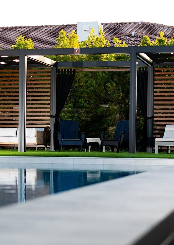 White cabana with privacy curtains beside a pool