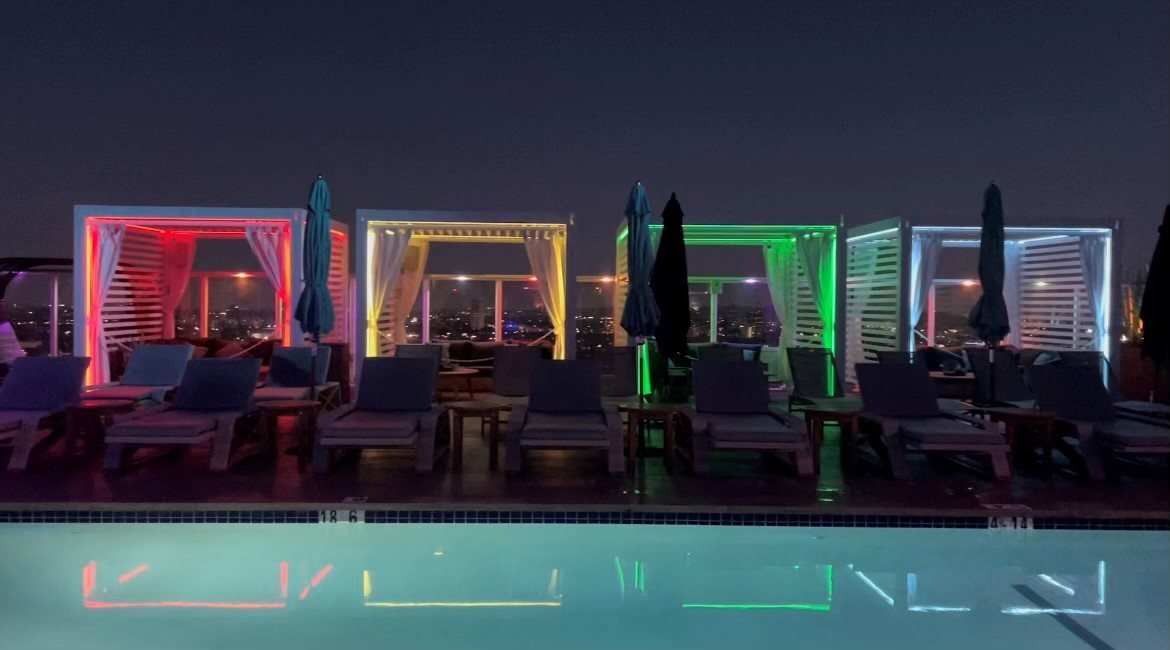 Rooftop pool lined with color-lit Cabana X cabanas