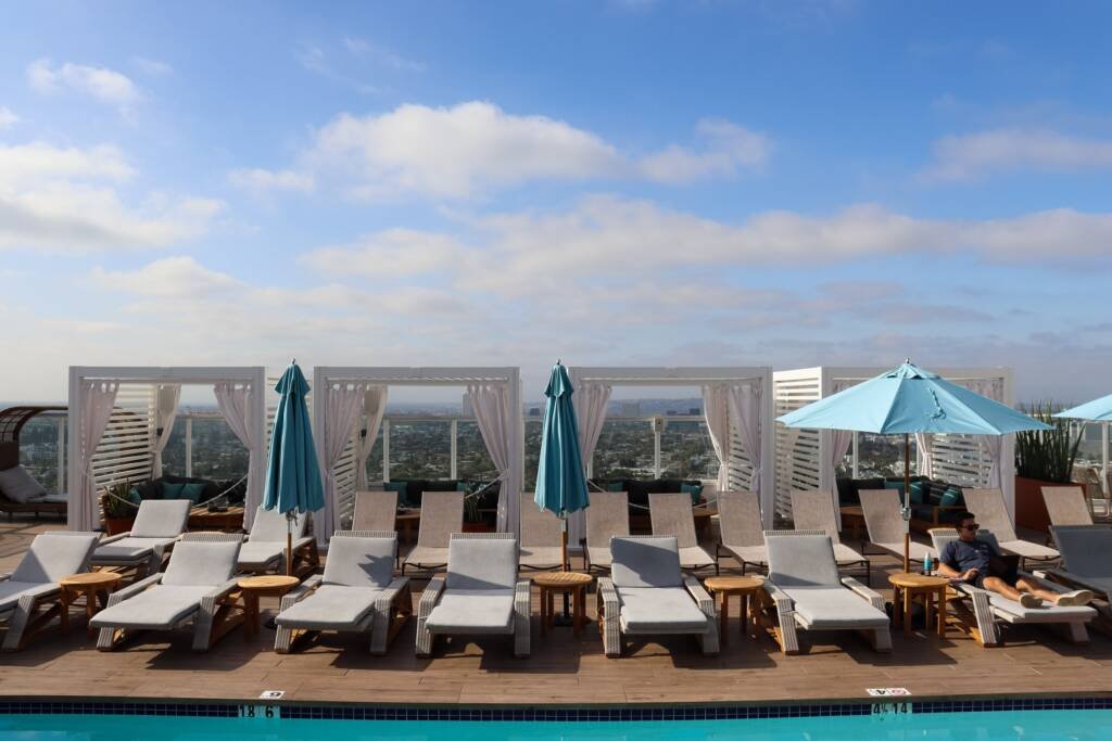 Cabana X cabanas behind loungers on a hotel rooftop deck